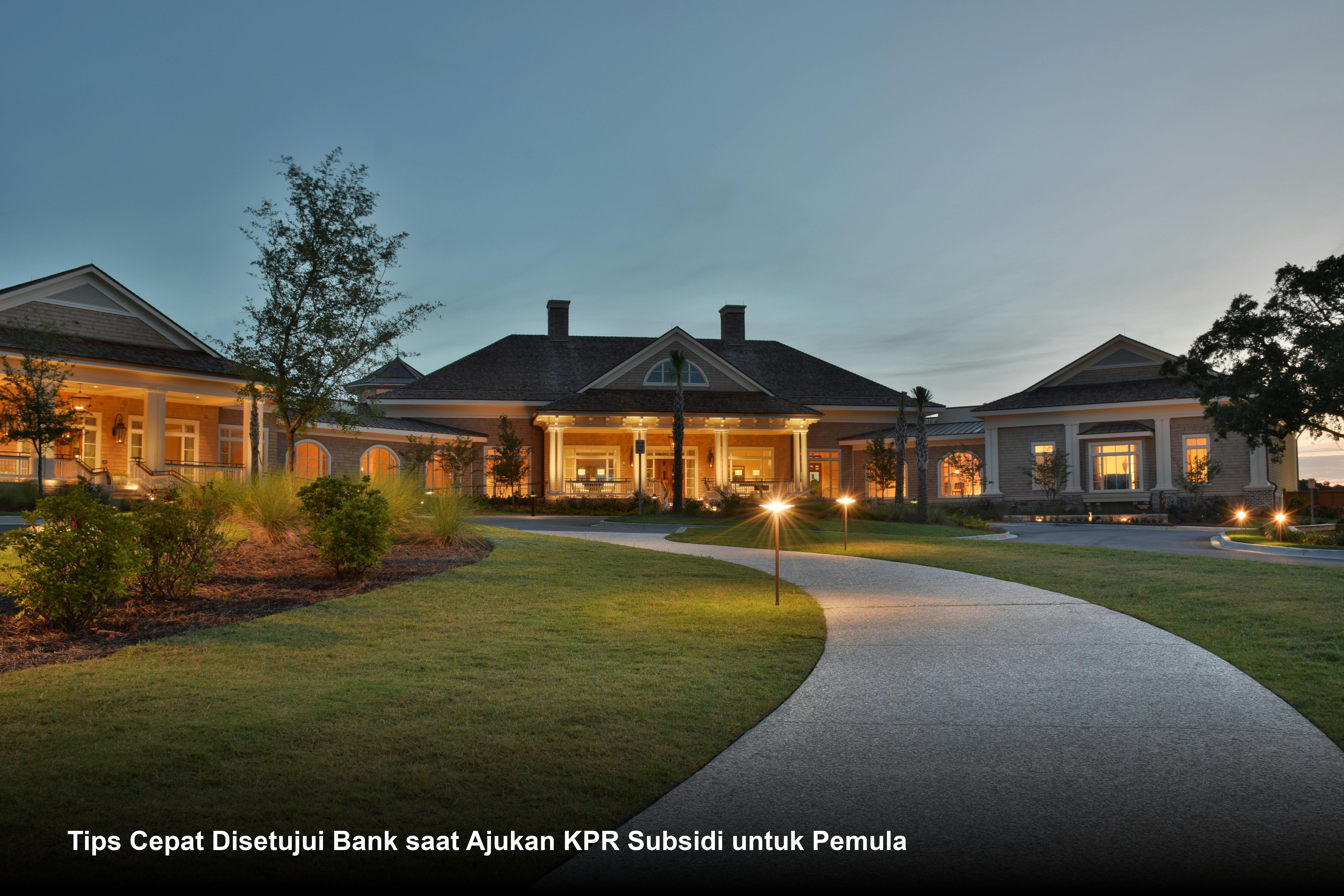 Seorang pasangan muda menandatangani dokumen akad kredit KPR di hadapan petugas bank dengan senyum bahagia.